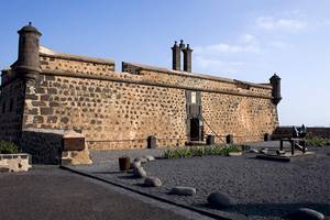 Außenansicht des Seaside Los Jameos Hotels mit einer steinernen Mauer, Tür und zwei Türmen.