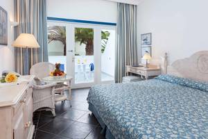 Innenansicht eines Schlafzimmers im Seaside Los Jameos Hotel mit Bett, Balkon, Tisch und Stühle.