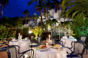 Abendessen im Freien im Seaside Los Jameos Hotel mit gedeckten Tischen und Palmen.