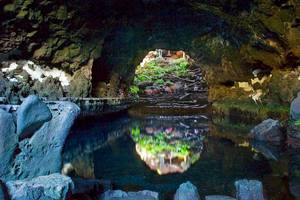 Eingang zur Grotte des Seaside Los Jameos Hotels mit kristallklarem Wasser und Besuchern.