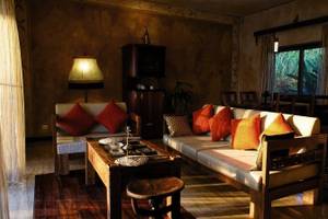 Wohnzimmer im Zanzi Resort mit Sofas, Tisch, Lampen und einem Blick auf den Garten.
