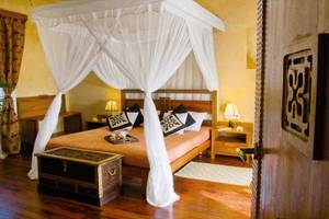 Ein luxuriöses Bettzimmer im Zanzi Resort mit einem Baldachin, einem Holzbett und Kissen.