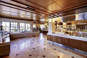 Innenansicht des Restaurants im Kalimera Kriti Hotel & Village Resort mit Marmorboden und Holzelementen.