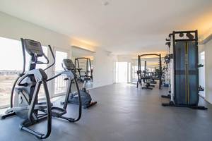 Fitnessraum im Hotel Dunas De Sal mit Geräten und Fenstern.