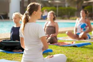 Frauen machen Yoga im Dunas De Sal Hotel vor einem Swimmingpool.