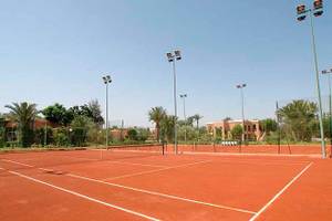 Tennisplatz im Royal Decameron Issil Resort mit roten Spielfeldern und Beleuchtungsmasten.