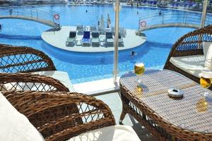 Außenbereich des Cenger Beach Resort & Spa mit Swimmingpool, Liegestühlen und Tischen.