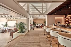 Innenansicht der Bar im Mare Ayia Napa Hotel mit Holzboden, modernen Stühlen und einer Theke.