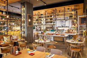 Innenbereich des Grand Hyatt Abu Dhabi Hotel Restaurants mit Holztischen, Stühlen und Regalen voller Flaschen.