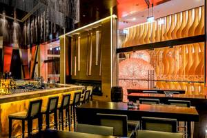 Innenbereich der Bar im Grand Hyatt Abu Dhabi Hotel mit goldenem Tresen und modernen Möbeln.