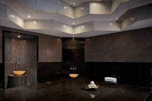 Innenansicht des Spa-Bereichs im Grand Hyatt Abu Dhabi Hotel mit schwarzen Fliesen und Holzbecken.