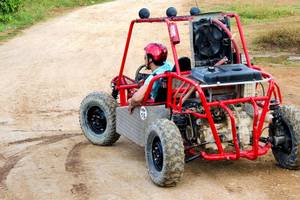 Mann im roten Helm fährt ein rotes Quad-Fahrzeug auf einem unbefestigten Weg im Barcelo Bavaro Beach Hotel.