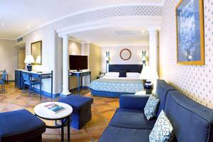 Innenansicht eines Hotelzimmers im Paradisus by Melia Gran Canaria mit einem Bett, Esstisch und Stühlen.