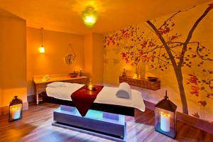Massage-Behandlungsraum im Titanic Deluxe Lara Hotel mit einem Therapiebett, Kerzen und dekorativen Elementen.