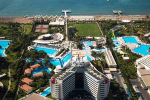 Luftaufnahme des Titanic Deluxe Lara Hotels mit Pools, Tennisplätzen und einem Meer im Hintergrund.