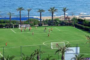 Fußballspiel auf einem Rasenfeld am Strand des Titanic Deluxe Lara Hotels.
