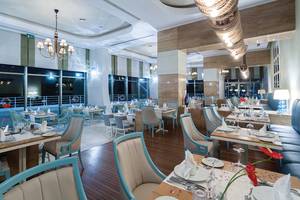 Innenansicht des Restaurants im Titanic Deluxe Lara Hotel mit blauen Stühlen und Tischen.