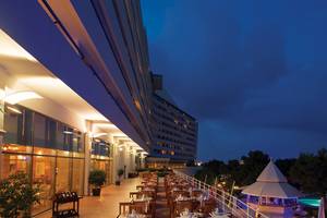 Abendliche Ansicht der Außenterrasse des Titanic Deluxe Lara Hotels mit gedeckten Tischen und Blick auf das Meer.