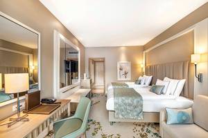 Modernes Hotelzimmer im Titanic Deluxe Lara mit zwei Betten, Schreibtisch und großem Spiegel.
