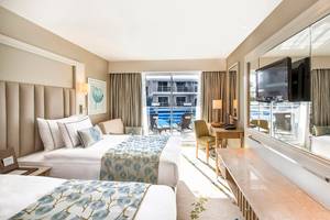 Ein Hotelzimmer des Titanic Deluxe Lara mit zwei Betten und Blick auf einen Pool.