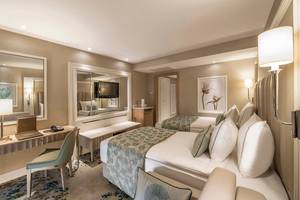 Hotelzimmer im Titanic Deluxe Lara mit zwei Betten, Schreibtisch, Spiegel und Fernseher.