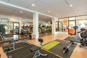 Fitnessstudio im Sunwing Kamala Beach Hotel mit verschiedenen Trainingsgeräten und einer Person, die Cardiogeräte benutzt.