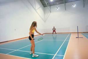 Im Reethi Beach Resort spielen zwei Personen Badminton auf einem Hallenplatz.