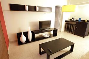 Wohnbereich eines Hotelzimmers mit Fernseher, Couch, Vasen und Tisch in einem modernen Innenraum.