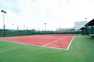 Ein leerer Tennisplatz im Freien mit grünem Boden und roten Markierungen.