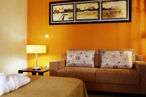 Zimmer im Valentin Varadero El Patriarca Hotel mit orangefarbener Wand, Couch, Lampe und Nachttisch.