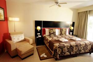 Zimmer im Valentin Varadero El Patriarca Hotel mit Bett, Stuhl, Nachttisch und Deckenventilator