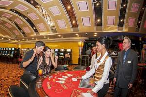 Casino mit Spielen und Spielern, darunter ein Mann und eine Frau, die am Tisch sitzen und spielen.