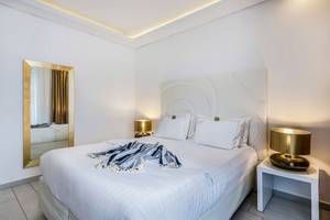 Schlafzimmer im Diamond Deluxe Hotel mit großem Bett, weißen Wänden und goldenem Spiegel.