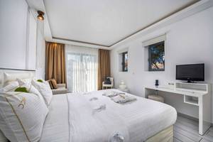 Schlafzimmer im Diamond Deluxe Hotel mit weißem Bett, Kissen, Fernseher und Schreibtisch.