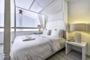 Innenansicht des Schlafzimmers im Diamond Deluxe Hotel mit vierposterbett, weißen Vorhängen und modernen Lampen.
