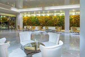 Lobby des Diamond Deluxe Hotels mit weißen Sofas und Tischen vor einer grünen Wand