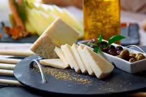 Gewürzter Käse auf einer schwarzen Schale mit Oliven und Gewürzen