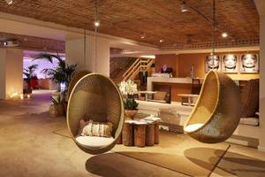 Lounge Bereich im ME Ibiza Hotel mit Hängesesseln, Pflanzen und einer Treppe.