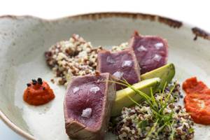 Gerecht im ME Ibiza Hotel mit Fleisch, Quinoa und Avocado auf einem Teller.