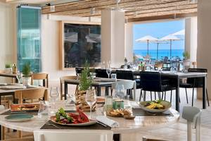 Innenbereich des ME Ibiza Hotels mit Blick auf das Meer und einem Esstisch mit Speisen.