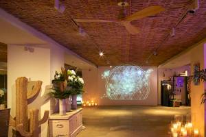 Innenraum des ME Ibiza Hotels mit Loungebereich, Projektion an der Wand, Pflanzen und Kerzen.