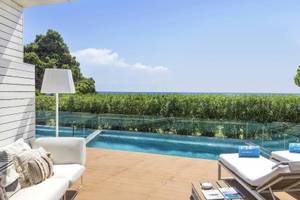 Außenbereich des ME Ibiza Hotels mit Pool, Loungemöbeln und Blick auf das Meer.