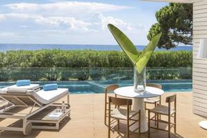 Terrasse des ME Ibiza Hotels mit Blick auf das Meer und eine begrünte Landschaft.