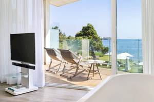 Innenansicht eines Zimmers im ME Ibiza Hotel mit Blick auf das Meer und Lounge-Stühlen.