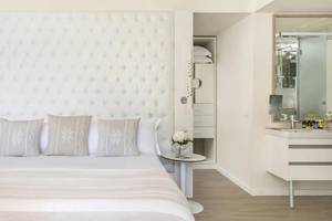 Schlafzimmer im ME Ibiza Hotel mit einem großen Bett, weißen Kissen und einem gepolsterten Kopfteil.