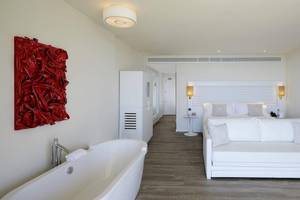 Innenansicht des Schlafzimmers im ME Ibiza Hotel mit Badewanne, Bett und Kunstwerk.