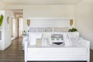 Ein modernes, helles Schlafzimmer im ME Ibiza Hotel mit weißen Möbeln und vielen Kissen.
