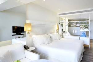 Innenansicht eines Zimmers im ME Ibiza Hotel mit zwei weißen Betten, einem Fernseher und einem Couchtisch.