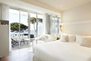 Innenansicht eines Zimmers im ME Ibiza Hotel mit Meerblick, inklusive eines großen Bettes und eines Tisches mit einer Telefon.