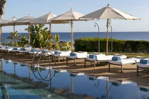 Poolbereich des ME Ibiza Hotels mit Sonnenliegen und Sonnenschirmen am Meer